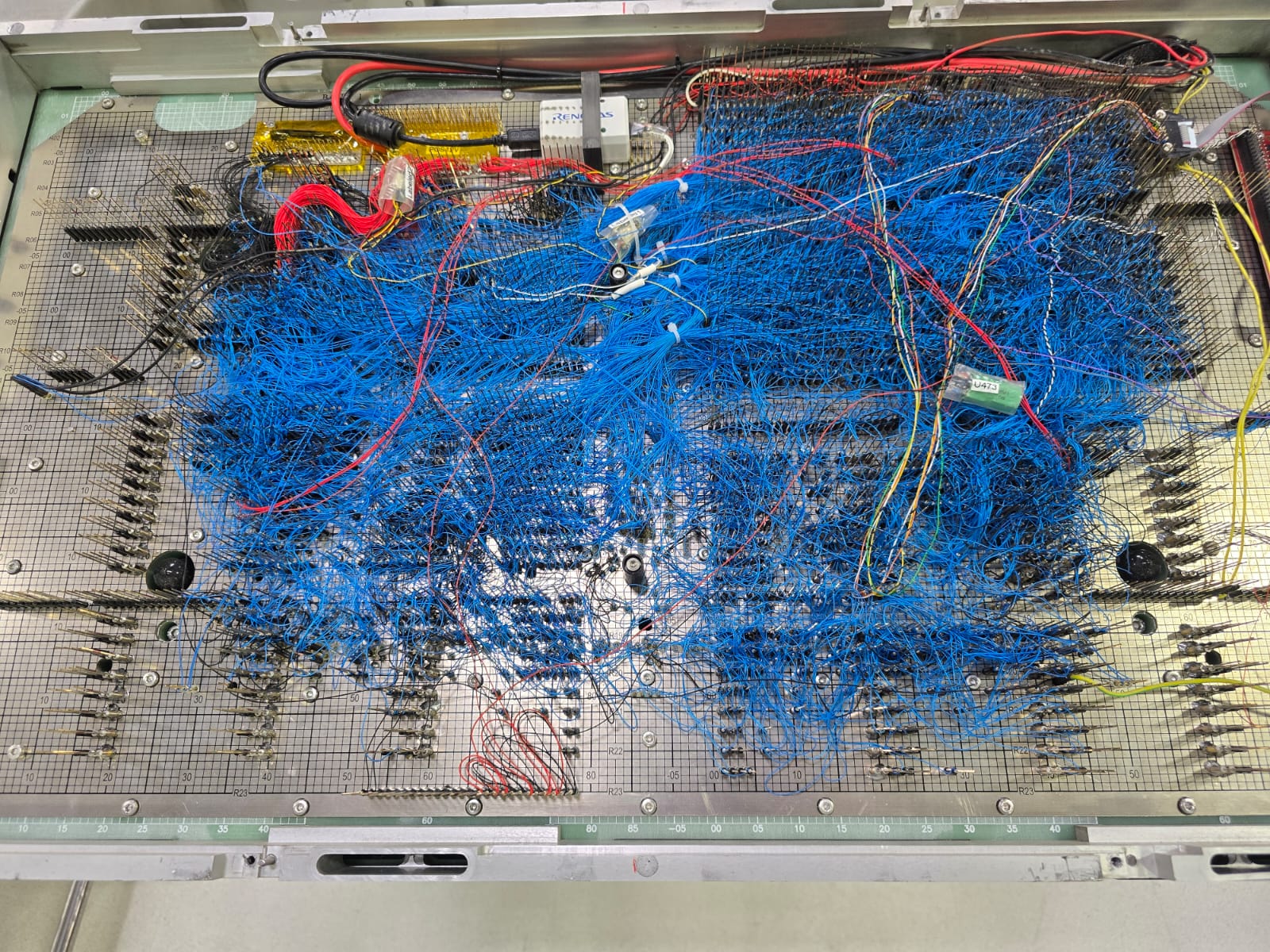 Vista superior de un fixture de ICT con cientos de hilos cableados hacia los pines de prueba